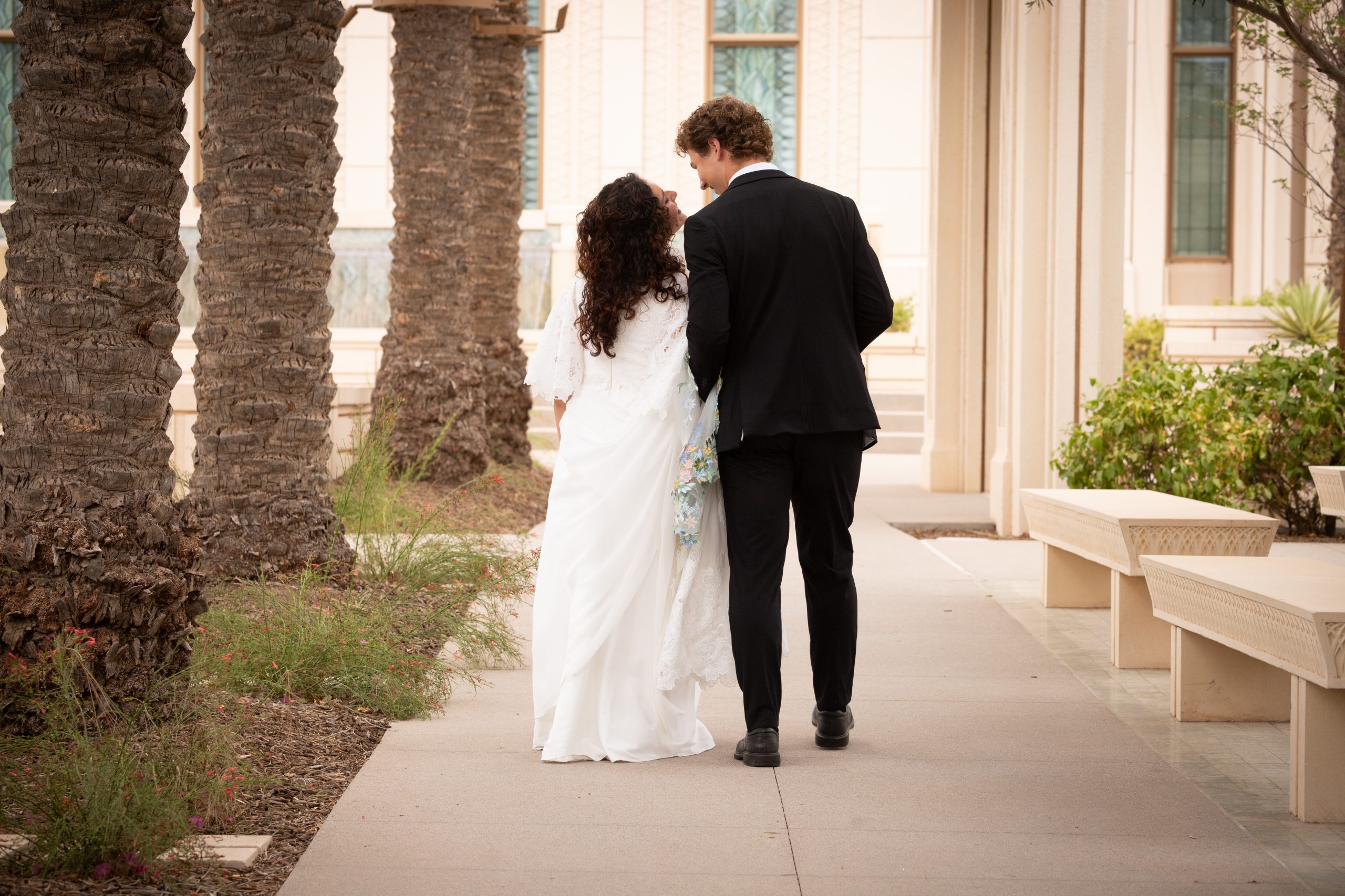 Bride and groom walking away while kissing at the Gilbert Arizona Temple